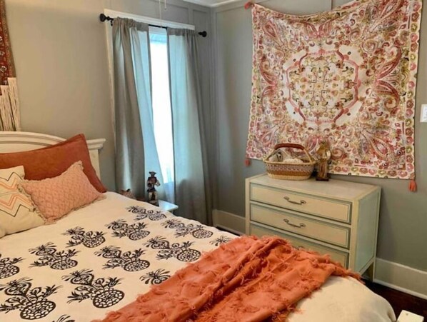 Relax in this serene bedroom with a comfortable bed, a dresser, and a decorative tapestry.