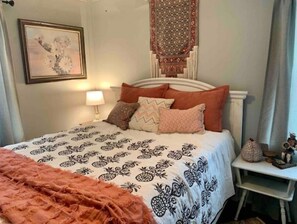 Cozy retreat with a neatly made bed, bedside table, and decorative wall hanging.