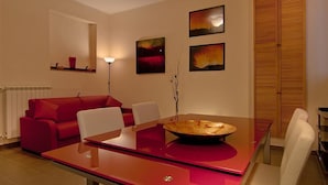 A modern dining area with a red table, white chairs, and a central decorative bowl.