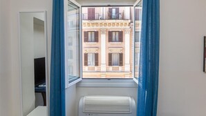 A room with a window overlooking a building with balconies.