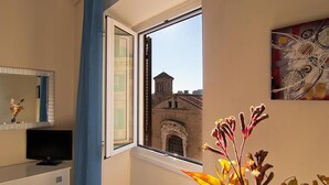 A room with a large window, a flat-screen TV, a mirror, and a painting.