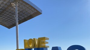 Un grande cartello esterno con la scritta "LOVE VIAS MEDITERRANEE" su un pontile di legno.