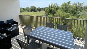 Una terrazza esterna con tavolo e sedie, un divano e vista su un paesaggio verde.