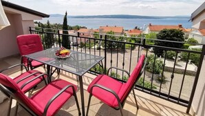 Un balcone con tavolo e sedie, vista su un corpo d'acqua e edifici circostanti.