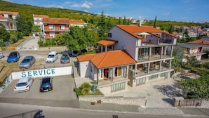 Un edificio a più piani con un ingresso di servizio e diverse auto parcheggiate.