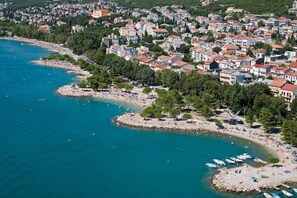 Luftaufnahme einer Küstenstadt mit Strand, Booten und Wohnhäusern.