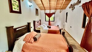 Een slaapkamer met twee bedden, houten balken in het plafond, een wandlamp en een lijst met een afbeelding.