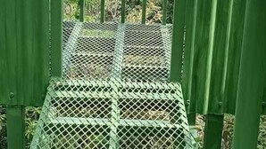 Een metalen trap die leidt naar een balkon met uitzicht over een veld en de lucht.