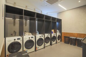 Filas de lavadoras de carga frontal en un lavadero público.