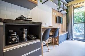 A modern kitchen with a built-in stove, a coffee maker, and a blender. There are two chairs and a small table.