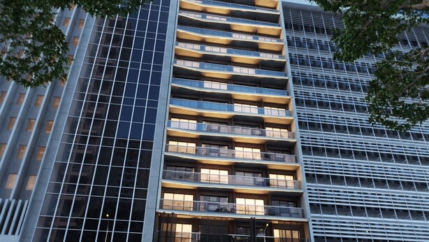 Un edificio moderno de gran altura con fachada en forma de cuadrícula, varios balcones y amplias ventanas.