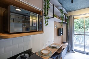 Una cocina moderna con microondas integrado, encimera de madera y comedor con mesa para dos.