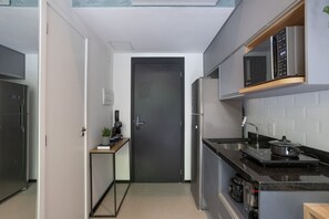 Una cocina compacta equipada con microondas, estufa y refrigerador.