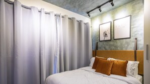 Una habitación de hotel con cama, cortinas y cuadros en la pared.