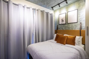 Una habitación de hotel con cama, cortinas y cuadros en la pared.