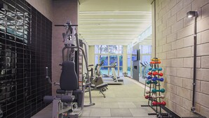 Un gimnasio con equipo de ejercicio, un rack de pesas y un ventanal que proporciona luz natural.