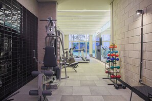 A gym with exercise equipment, a weight rack, and a window providing natural light. - VN Consolação (São Paulo)