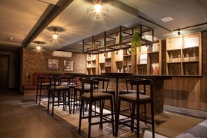 Zona de bar con taburetes, estanterías con cristalería y una planta colgante.