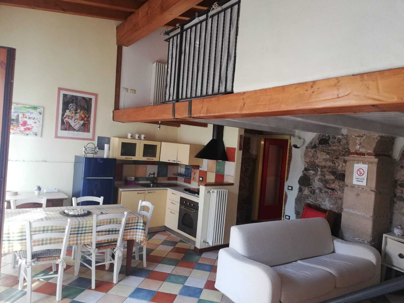 Une cuisine chaleureuse avec un coin repas, un canapé et un escalier menant à l’étage supérieur.