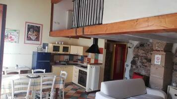 A cozy kitchen with a dining area, a sofa, and a staircase leading to an upper level.