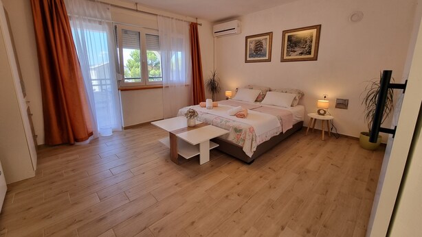 Une chambre à coucher avec un lit, des tables de chevet, un bureau et une fenêtre avec des rideaux.