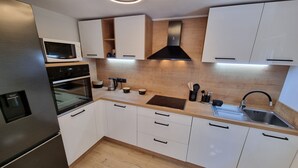 Une cuisine moderne avec des armoires blanches, un réfrigérateur en acier inoxydable, un four, une cuisinière et un évier.