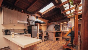 A kitchen with a brick oven, a microwave, and wooden beams. - Refugio Cumanda  Lodge (San Pablo del Lago)