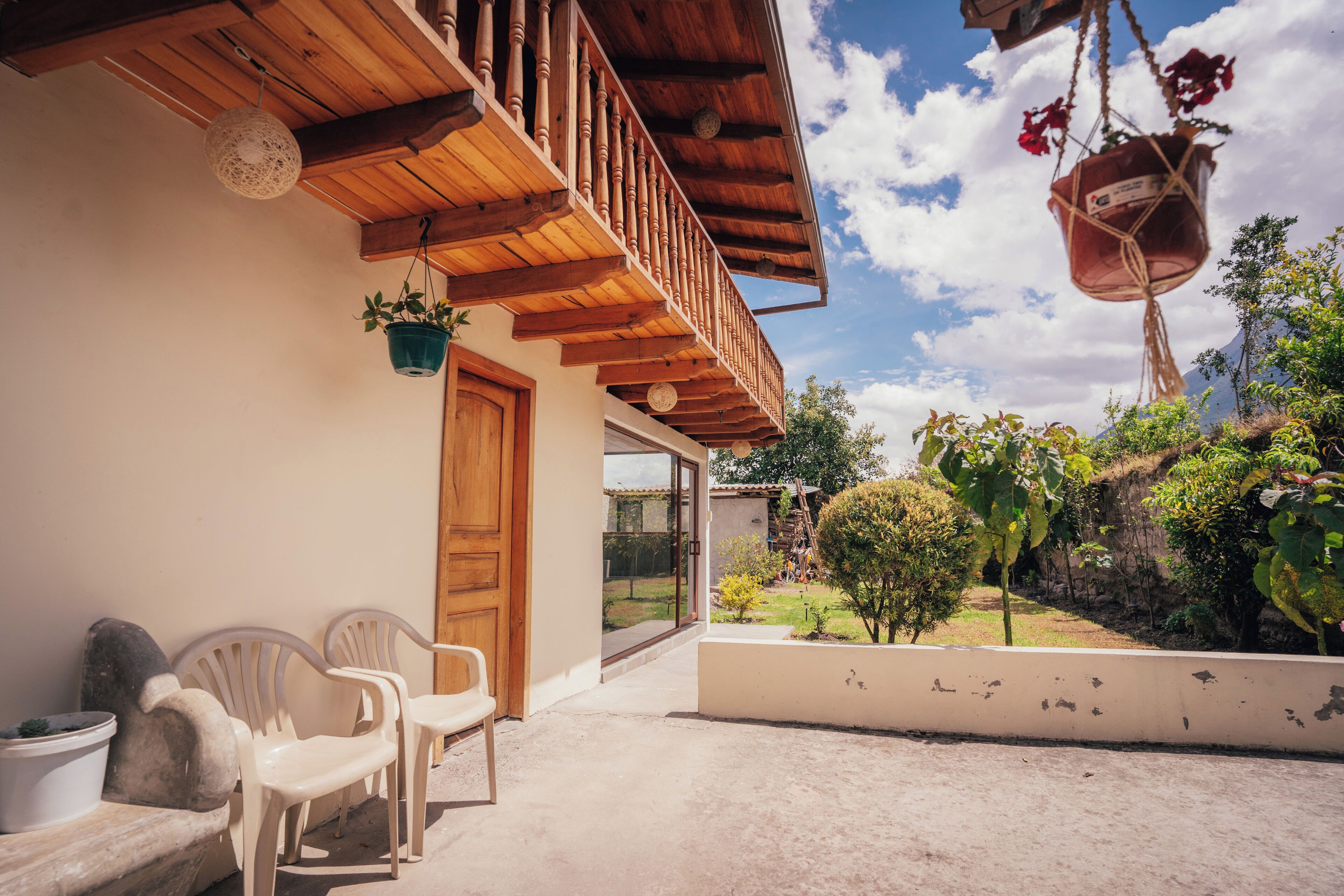 A wooden balcony with a view of a garden and a mountain.