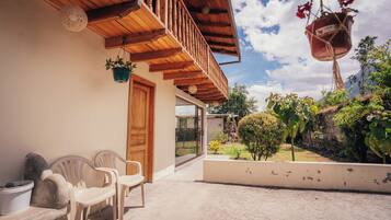 A wooden balcony with a view of a garden and a mountain.