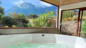A hot tub under a wooden roof with a view of mountains. - Refugio Cumanda  Lodge (San Pablo del Lago)