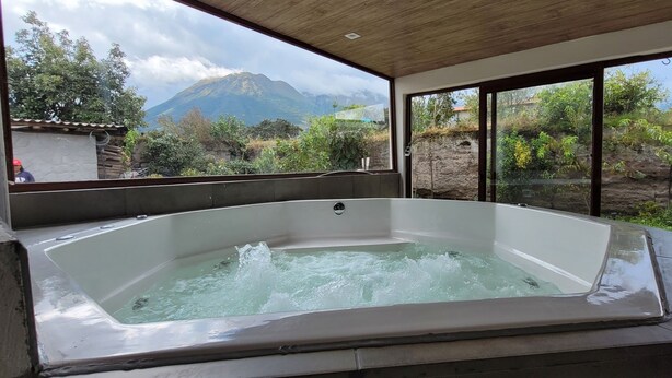 A hot tub with a view of a mountain and surrounding vegetation. - Refugio Cumanda  Lodge (San Pablo del Lago)