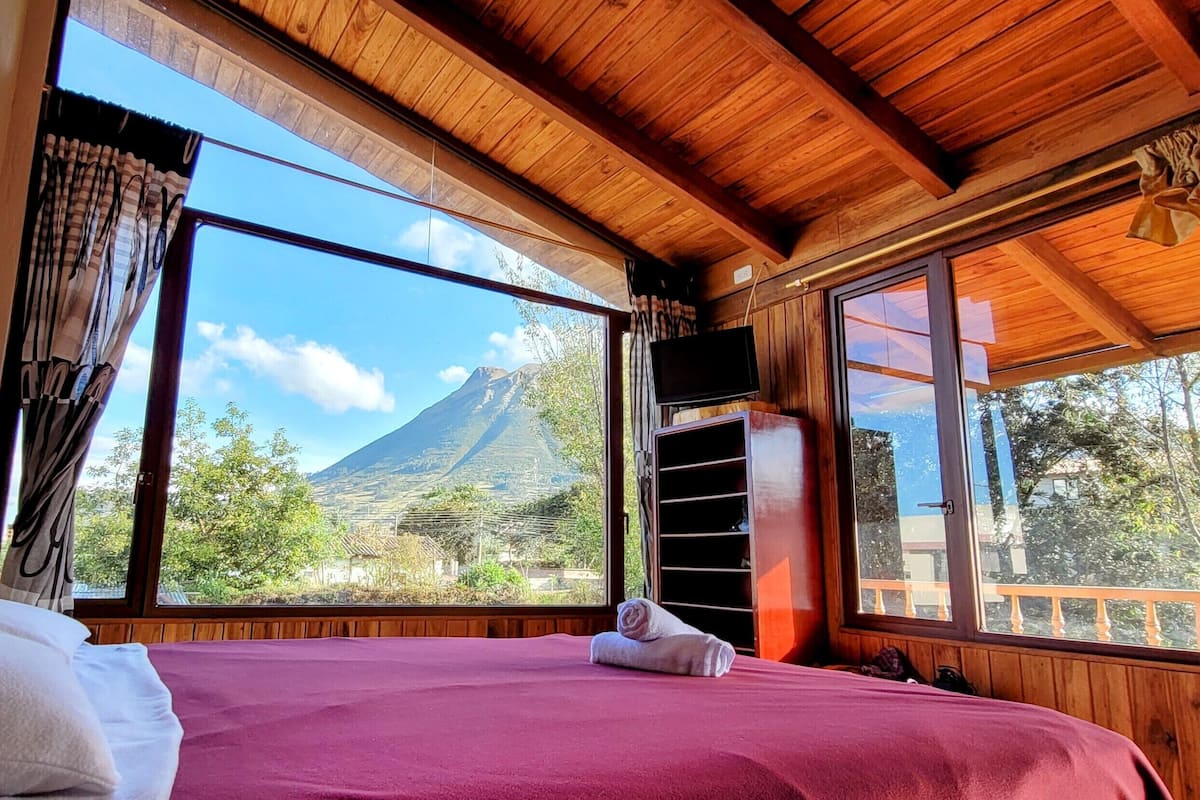 A bedroom with a bed, large windows, and a view of a mountain.