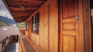 A wooden building with a balcony, large windows, and a door with a lock. - Refugio Cumanda  Lodge (San Pablo del Lago)