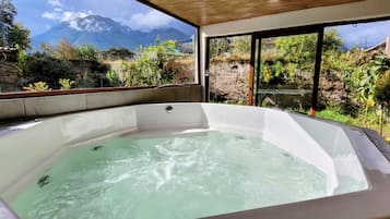 A hot tub with a view of mountains and greenery.
