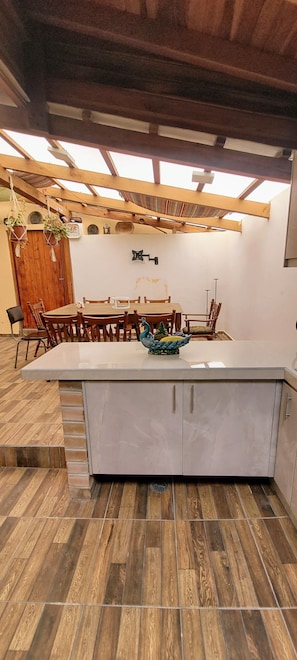 Una cocina con isla central, mesa de comedor de madera y sillas.