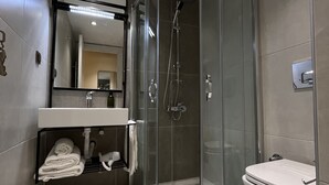 A modern bathroom with a glass-enclosed shower, a toilet, and a sink with a towel rack. - Sezer's Oliva Hotel (Ezine)