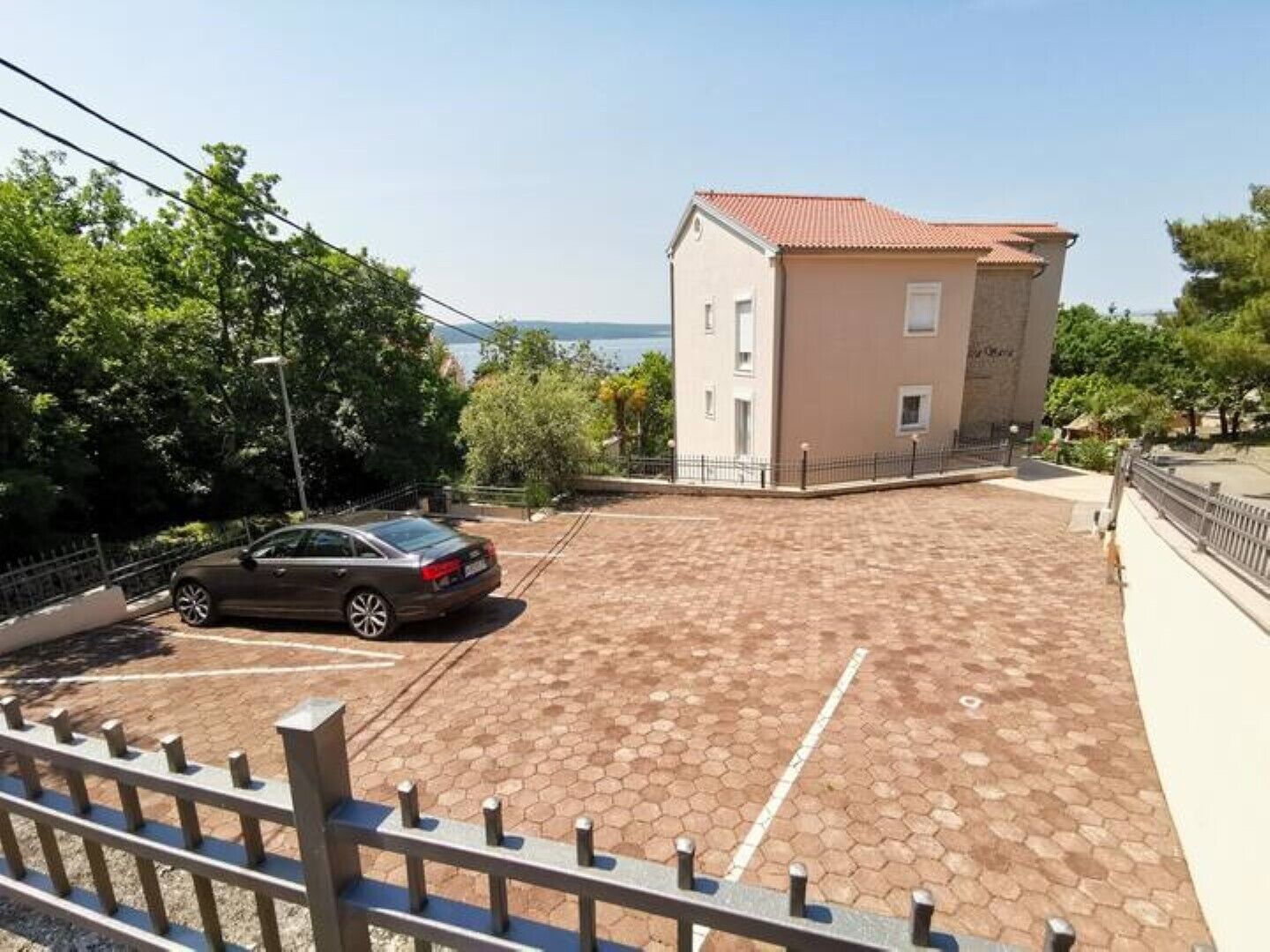 A building with a tiled roof and a parking area with a car.