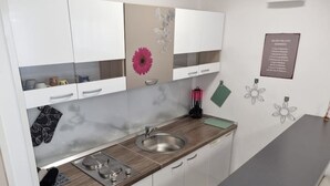 Una cucina moderna con mobili bianchi, un lavello in acciaio inox e un piano di lavoro in legno.
