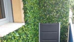 A small, enclosed outdoor seating area with a black chair and a green hedge wall. - Le 182 Promenade du Soleil, Tout Juste Rénové, Azur Riviera (Menton)