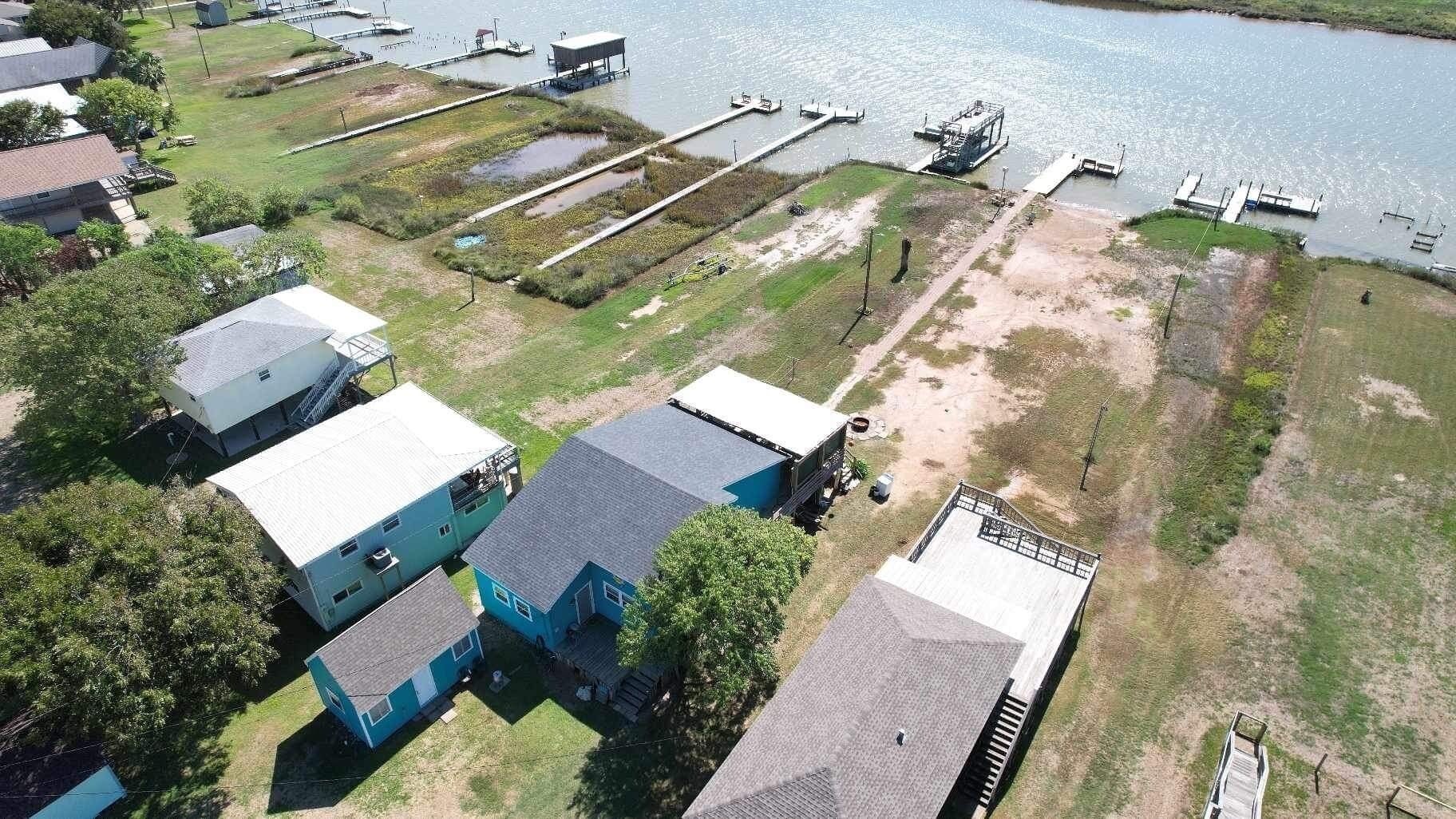 An aerial view of a residential area with houses, a dock, and a body of water.