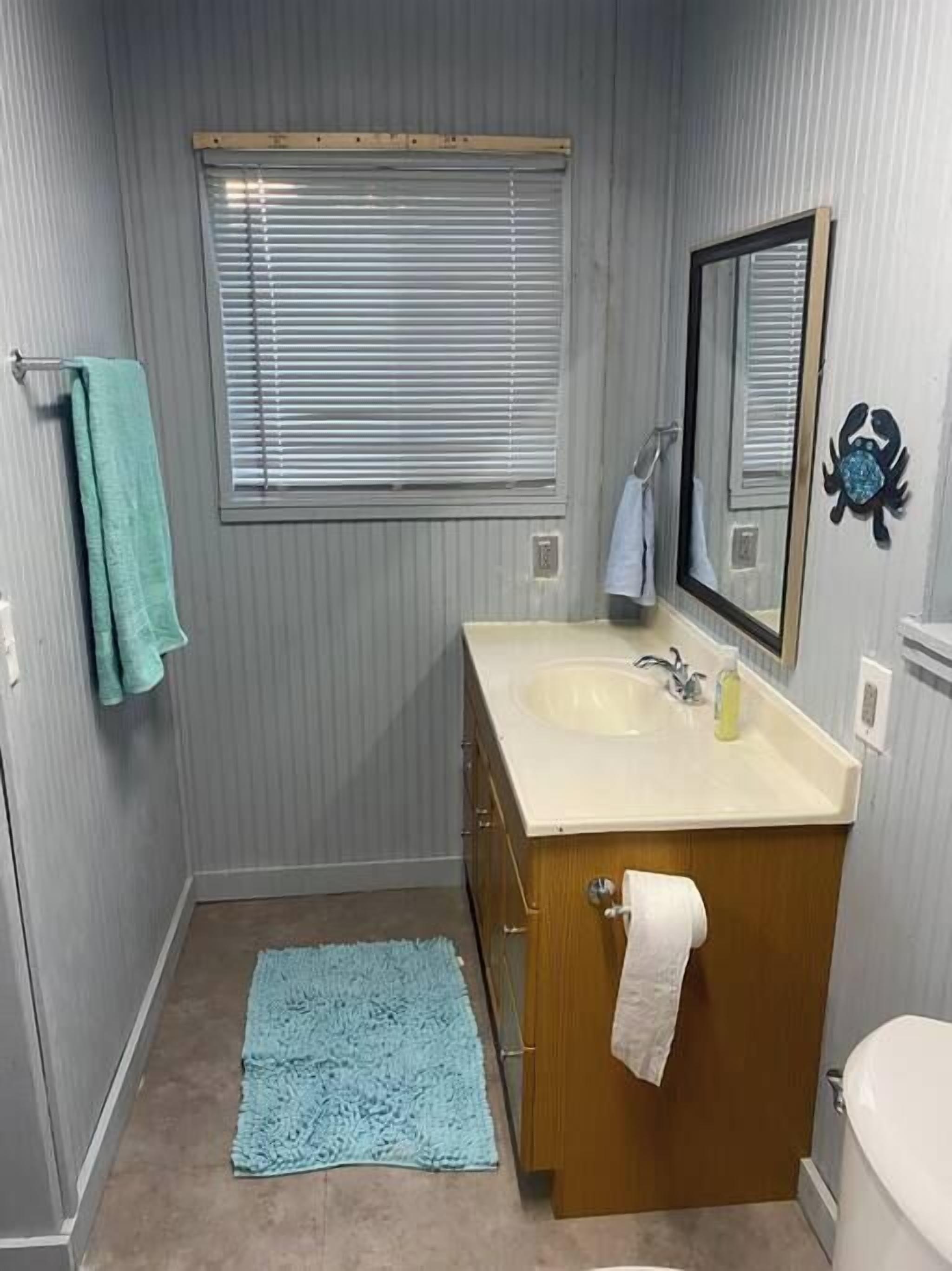 Ein kleines Badezimmer mit einem Holztischchen, einem Waschbecken, einem Spiegel und einer Toilette.