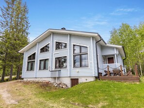 A two-story log cabin with a porch and a small deck, surrounded by trees. - Kuusipirtti by Interhome (Puolanka)