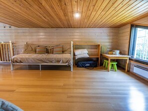 A room with a wooden ceiling, a bed with a metal frame, a small table with a chair, and a window. - Kuusipirtti by Interhome (Puolanka)