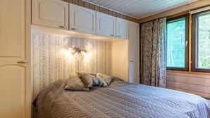 A bedroom with a large bed, a wardrobe, and a window with curtains. - Kuusipirtti by Interhome (Puolanka)