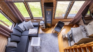 A modern log cabin interior with a sectional sofa, a fireplace, a dining area, and a staircase. - Kuusipirtti by Interhome (Puolanka)