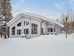 A two-story log cabin with a steep roof, large windows, and a covered driveway. - Kuusipirtti by Interhome (Puolanka)
