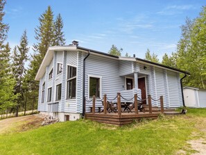 A log cabin with a porch, a deck, and a small shed in a wooded area. - Kuusipirtti by Interhome (Puolanka)