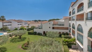A residential building with multiple balconies, a swimming pool, and well-maintained gardens.