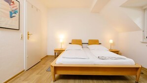 Een slaapkamer met een houten bed, twee nachtkastjes met lampen, een deur en een lijst met een foto aan de muur.