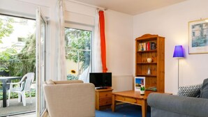 Un salon avec un canapé, un téléviseur, une bibliothèque et une lampe.